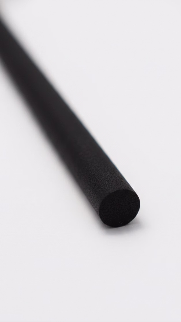 Black cylindrical diffuser refill reed on a clean white surface