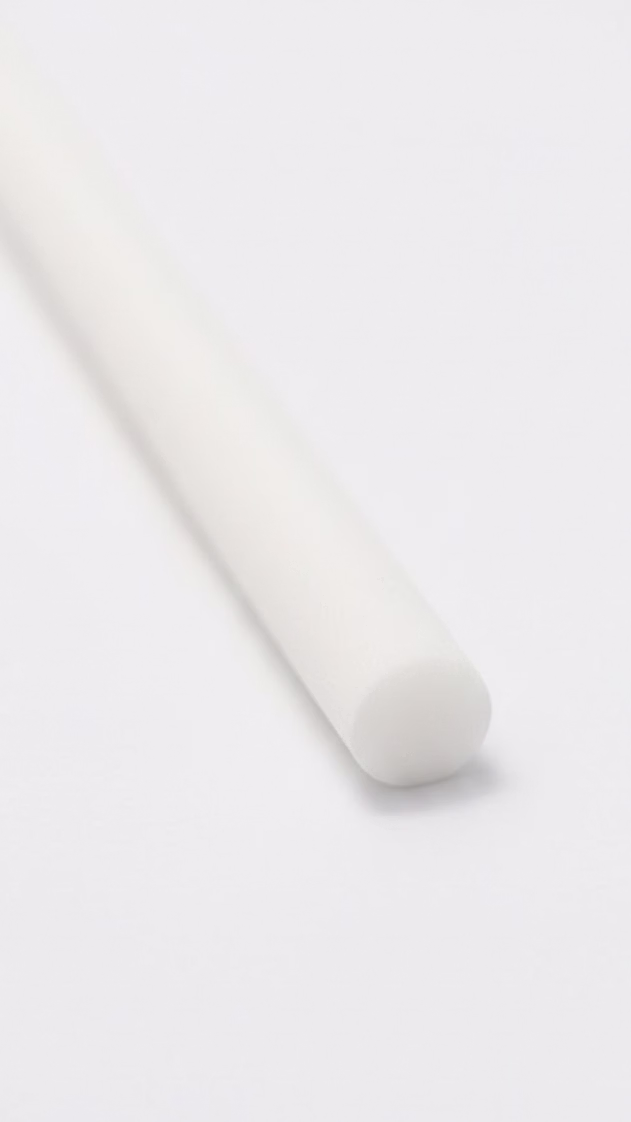 White cylindrical diffuser refill reed on a clean white surface in a minimalist setting